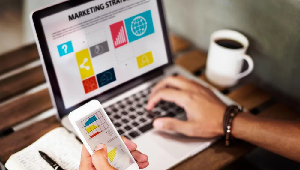 Ilustrasi perencanaan marketing strategy: orang bekerja dengan laptop dan smartphone untuk membangun identitas brand