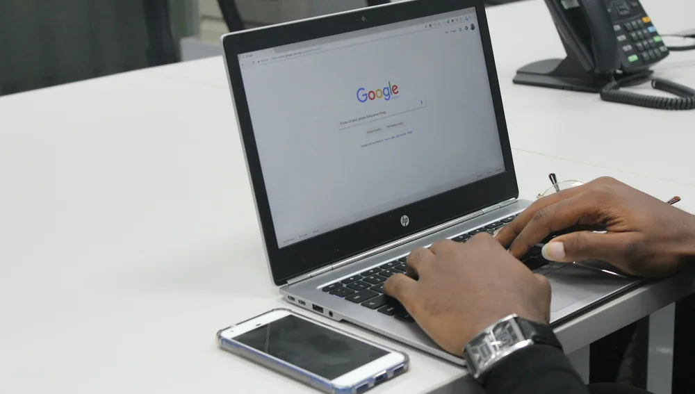 Orang mengetik di laptop dengan halaman mesin pencari Google untuk riset kata kunci SEO