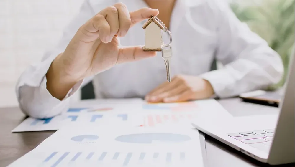 Agen properti memegang maket rumah, gambaran strategi pemasaran properti untuk hunian dan ruko