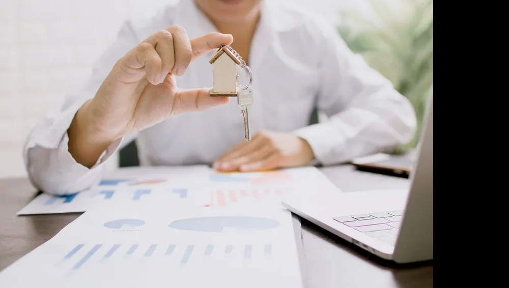Agen properti memegang maket rumah, gambaran strategi pemasaran properti untuk hunian dan ruko